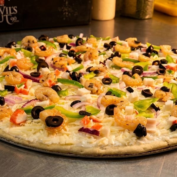Uncooked pizza topped with shrimp, crab, black olives, green peppers, red onions, and cheese.